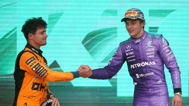Kimi Antonelli and Lando Norris exchange a handshake on the Miami GP podium, Antonelli in Mercedes purple and Norris in McLaren orange