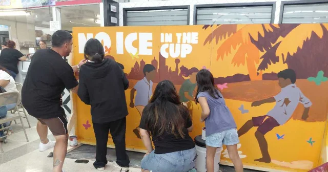 Community members paint a No ICE in the Cup mural