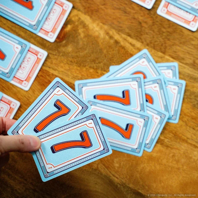 A hand holding matching rank cards above a Tap 4 stack on a wooden table.