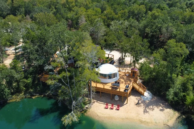 Aerial view of The Fairy House's dome, deck, trees, and cove-side setting