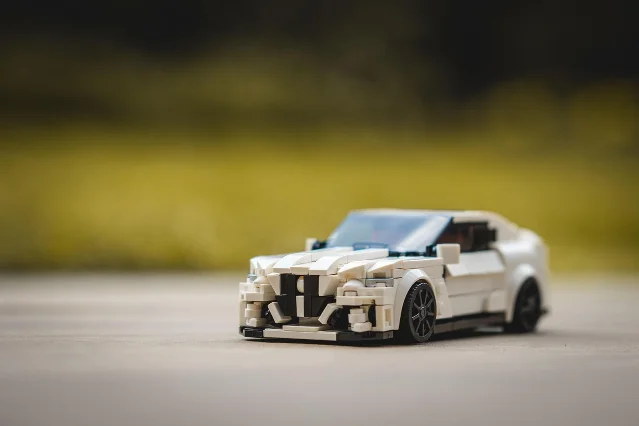 LEGO Speed Champions car model on pavement with shallow depth of field, green bokeh background — generic LEGO automotive set photography