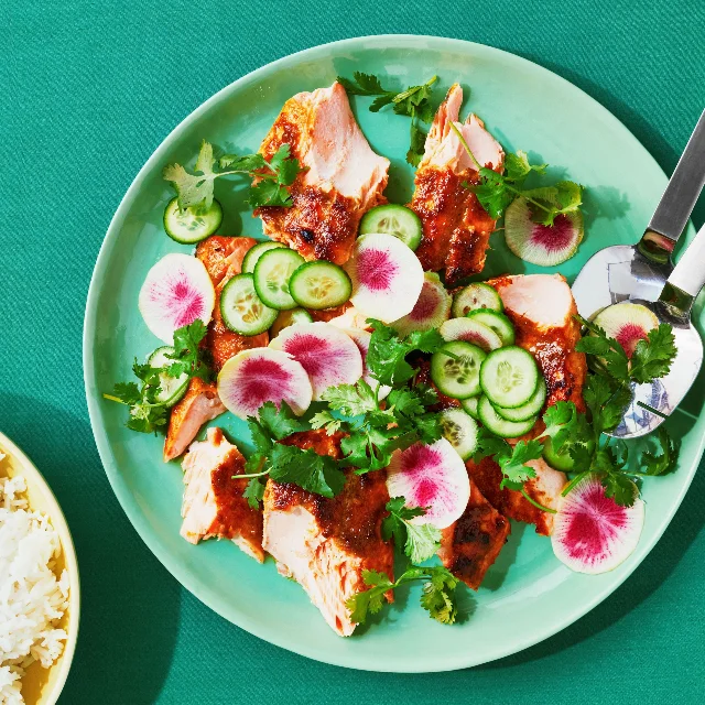 Broiled green curry–glazed salmon broken into portions with cucumber and radish slices