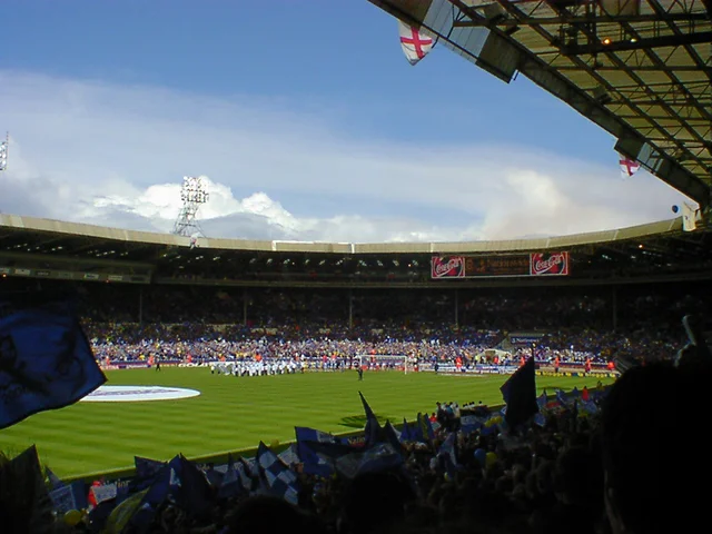 "A crowd of football supporters in a stand waving blue and white flags and banners"