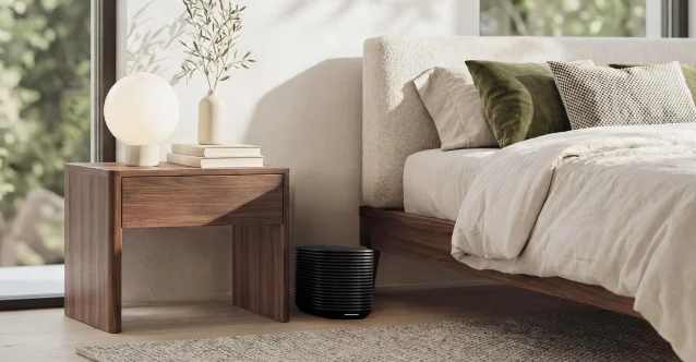 The Eight Sleep Pod 6 hub, a ribbed black cylinder, sitting under a bed