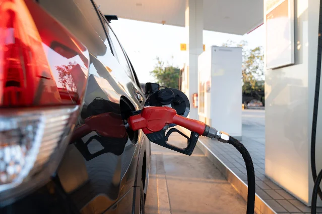 A hand-held fuel nozzle filling a car at a gas station pump