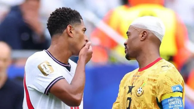 Jude Bellingham covers his mouth while speaking to Jordan Ayew