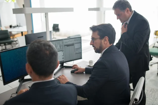 Analysts reviewing market data on multiple screens at a trading desk