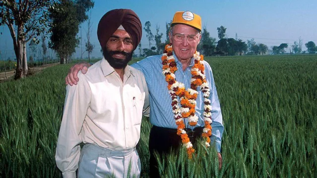 Norman Borlaug with an Indian farmer in a wheat field.