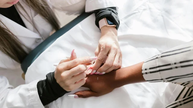 Acupuncture needles applied to a person's hand during a clinical wellness session