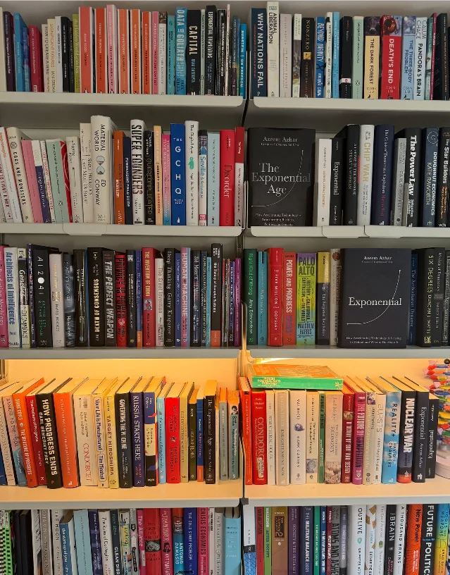 A bookshelf filled with books on economics, politics, technology, and society