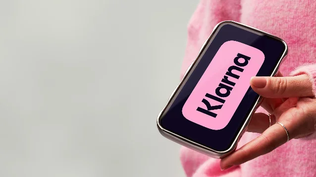 Klarna 官方发布图中,一位用户手持手机使用 Klarna 应用