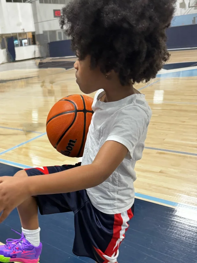 A child holds a basketball in a gym in a photograph published on the Sole Scholars Foundation's official website.