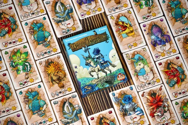Bloom Kingdom cards fanned around the box on a wooden table