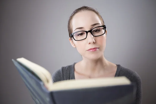 A woman reading an open book close to the camera