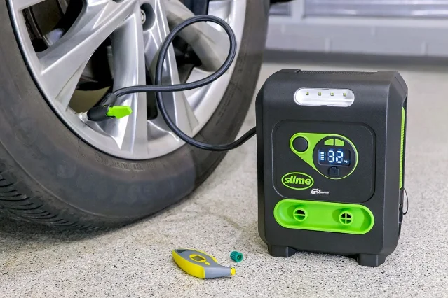 A portable tire inflator connected to a car tire at the valve stem