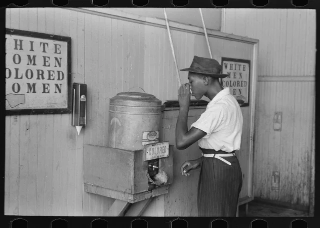 Russell Lee's 1939 photograph of a Black man drinking at a segregated water cooler in Oklahoma City.