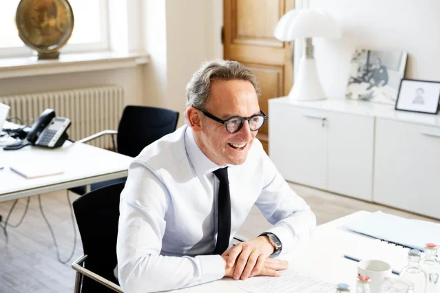 Boris Dilliès seated at a desk in a white shirt and dark tie