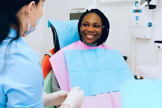 A smiling dental patient in a treatment chair talking with her dental hygienist before a procedure