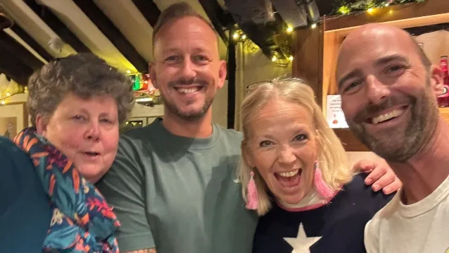 Four people posing together inside a pub.