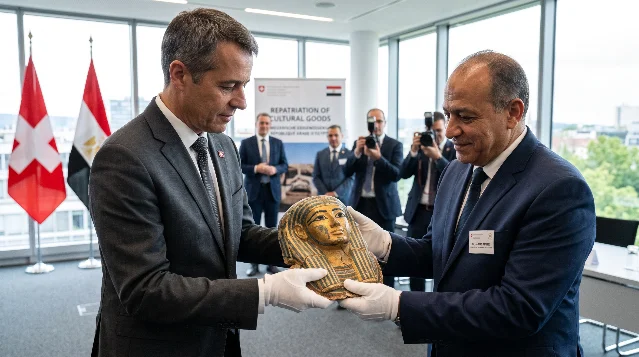 Officials in white gloves holding a gilded Egyptian funerary mask at a handover ceremony