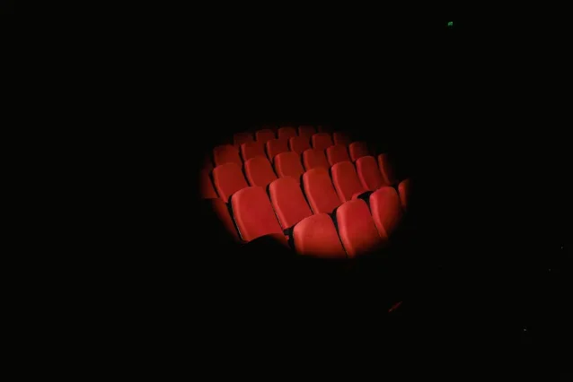 Red cinema theater seats illuminated in a darkened auditorium
