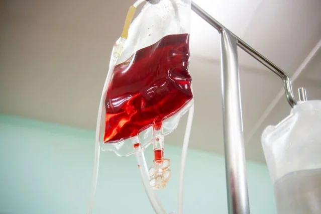 Red-cell blood transfusion bag on IV stand in a surgical setting