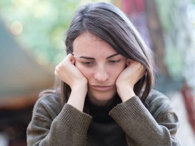 Young woman looking pensive and thoughtful, sitting outdoors