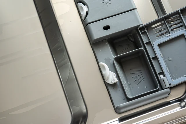 Open dishwasher detergent dispenser cup on the door