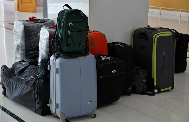 Open suitcase packed with rolled clothes, shoes, and travel accessories