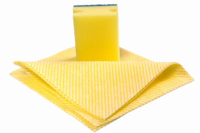 A yellow sponge standing on a folded cleaning cloth
