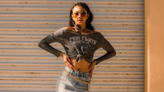A knotted graphic crop top styled with jeans and a chain belt
