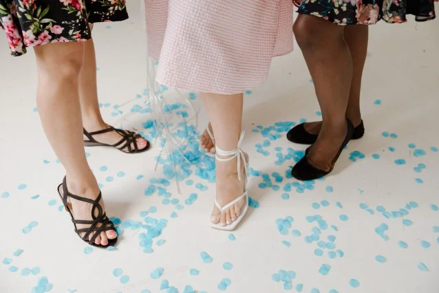 Strappy sandals and summer shoes worn at a fashion event — confetti-scattered white floor