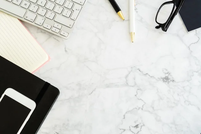 A plain work desk with notebook and pen — a writer's workspace, sparse and focused