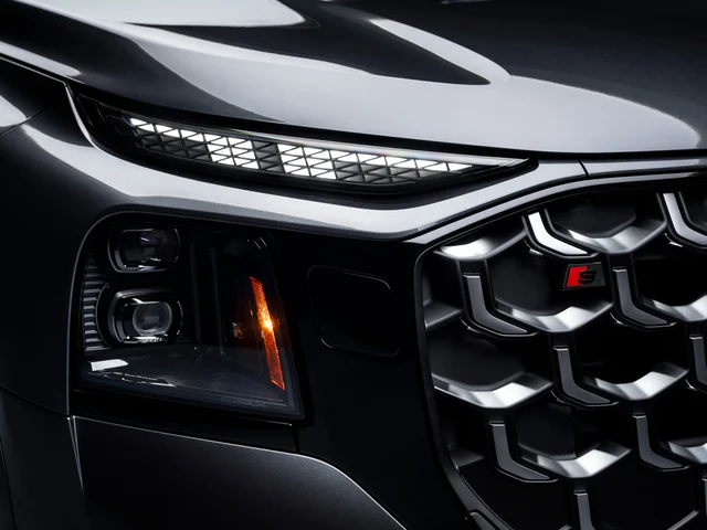 A close-up of an Audi SQ9 headlight cluster with an illuminated LED daytime running strip above projector lenses and an amber side marker