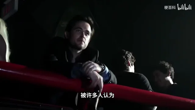 昏暗的酒吧里，一位卷发男子趴在二楼的红色栏杆上往下看，背景是模糊的人影，底部字幕是「被许多人认为」