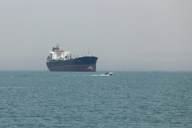 Oil tanker anchored near the Strait of Hormuz with a fast boat passing in the foreground