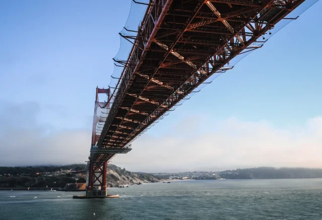 Underside of the Golden Gate Bridge showing the red steel stiffening truss and lateral bracing system