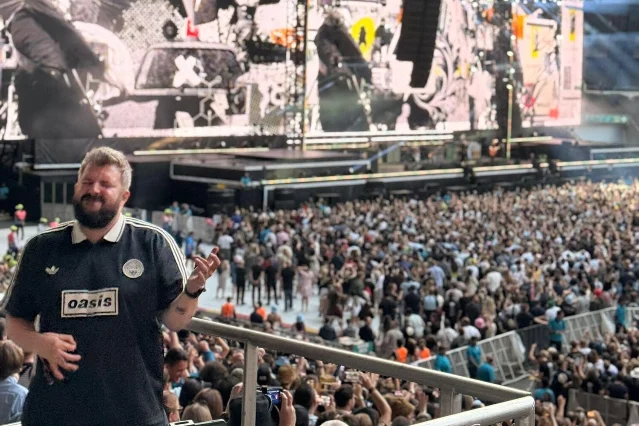 Luke Holdsworth gestures toward the crowd while interpreting at an Oasis concert