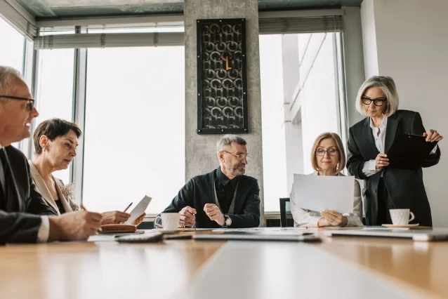 Business professionals reviewing documents around a boardroom table