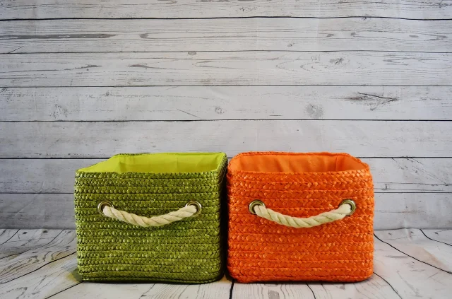 Two woven storage baskets on a light wood surface.