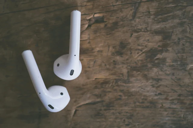 Close-up of white wireless earbuds on a wooden surface
