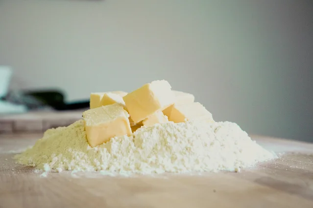 Flour heaped on a wooden board with cubes of butter pressed into it