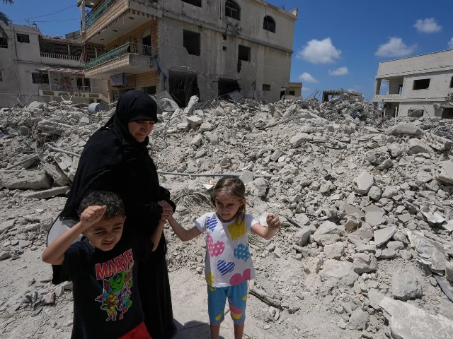 A family walks past a destroyed home in southern Lebanon