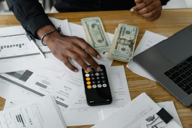 Overhead view of financial documents with calculator, cash, and laptop — a healthcare financial planning flat lay