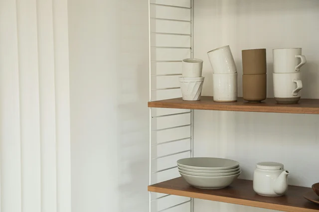 Ceramic tableware on wooden shelves — clean, minimal retail display