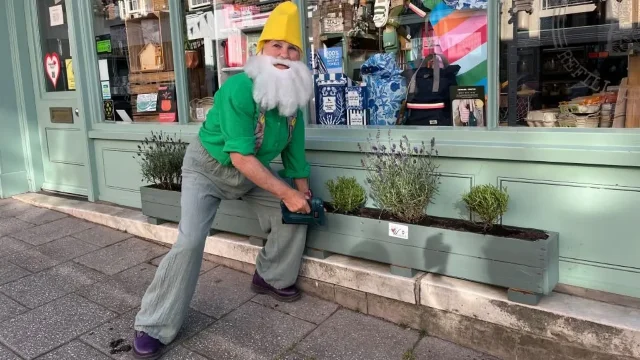 Councillor Sue Sealy installs a planter outside a shop in Whitchurch while dressed as a garden gnome.