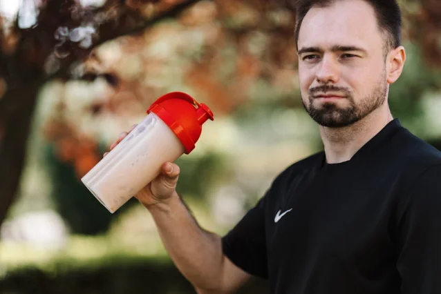 Man holding a protein shake tumbler outdoors