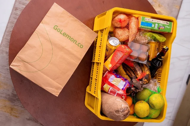 A GoLemon grocery bag beside a crate of household groceries.