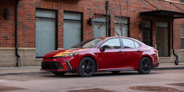 Red Toyota Camry Hybrid sedan parked on a city street