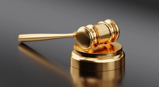 Judge's gavel on a wooden bench surface